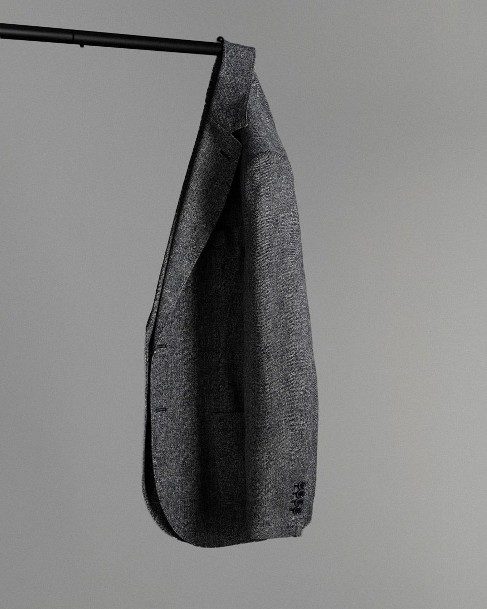 Dunkelgrau meliertes Herren-Sakko hängt am Ende einer schwarzen Stange vor schlichtem grauem Hintergrund.