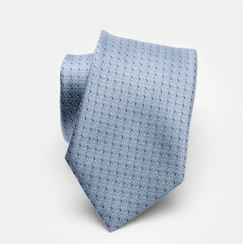 Hellblaue Seidenkrawatte mit feinem, geometrischem Muster aus kleinen Ovalen, locker eingerollt auf weißem Hintergrund.