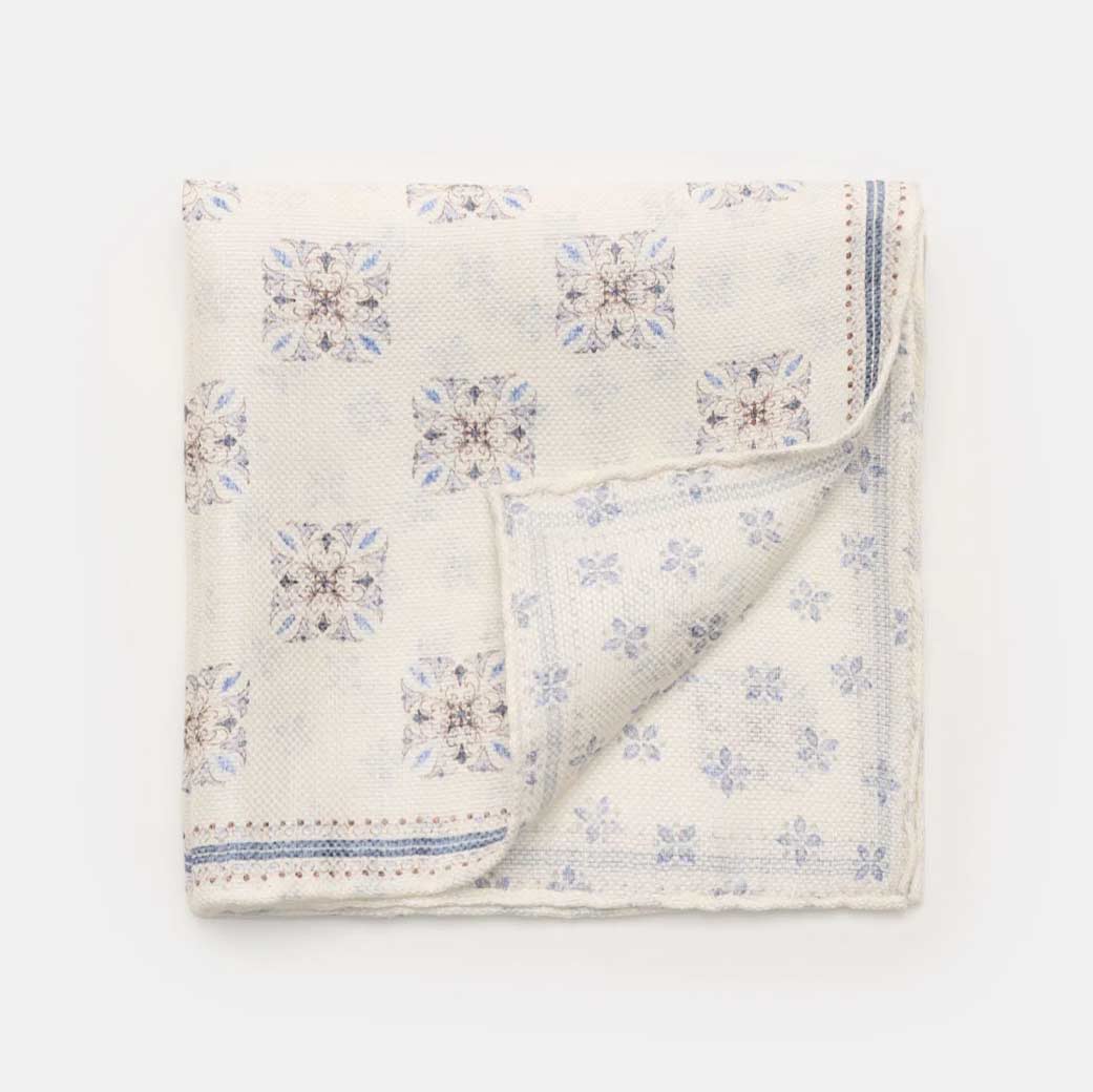 Beiges Einstecktuch mit braun-blauem Blumenmuster, feiner Struktur, Ecken umgeschlagen, dezente Bordüre am Rand.