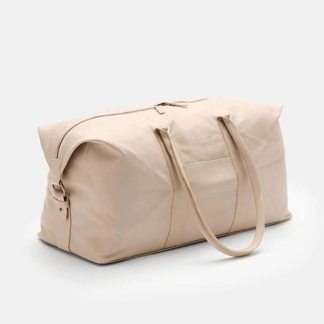 Großer Weekender aus beigem Leder mit Reißverschluss, zwei langen Tragegriffen und schlichter, eleganter Optik.