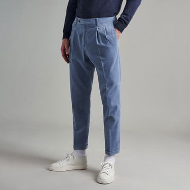 Mann trägt hellblaue Hose, weiße Sneaker, weiße Socken und navyblauen Pullover, steht vor grauem Hintergrund. Mann trägt hellblaue Hose, weiße Sneaker, weiße Socken und navyblauen Pullover, steht vor grauem Hintergrund.