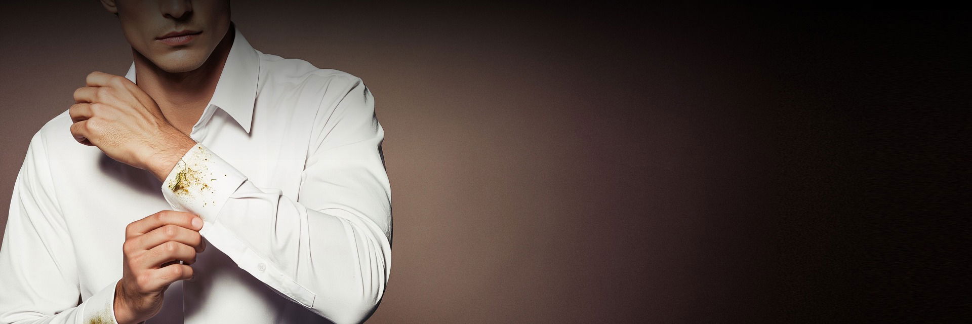 Mann trägt weißes Hemd mit Grasflecken und Schmutz am linken Hemdärmeln, vor dunklem Hintergrund. Mann trägt weißes Hemd mit Grasflecken und Schmutz am linken Hemdärmeln, vor dunklem Hintergrund.