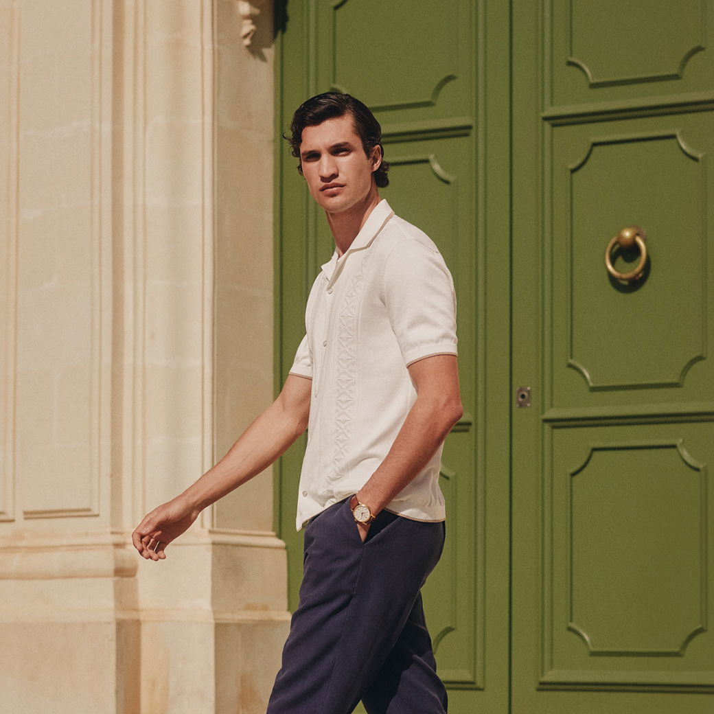 Mann mit weißem Kurzarmhemd und blauer Hose geht vor großer grüner Tür aus Holz mit Messinggriff. Mann mit weißem Kurzarmhemd und blauer Hose geht vor großer grüner Tür aus Holz mit Messinggriff.