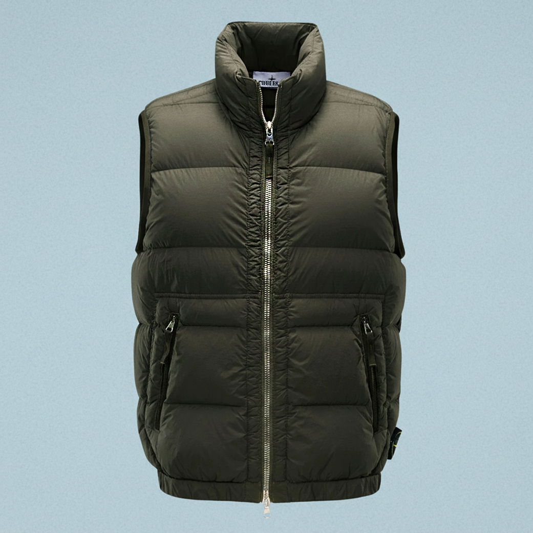 Herren Daunenweste in Olivgrün mit Stehkragen, durchgehendem Reißverschluss und seitlichen Reißverschlusstaschen vor hellblauem Hintergrund. Herren Daunenweste in Olivgrün mit Stehkragen, durchgehendem Reißverschluss und seitlichen Reißverschlusstaschen vor hellblauem Hintergrund.