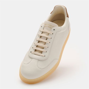 Herren-Sneaker aus weiß-beigem Glattleder mit Flügelkappe, hellbeiger Gummisohle und braunem Fersen-Detail.