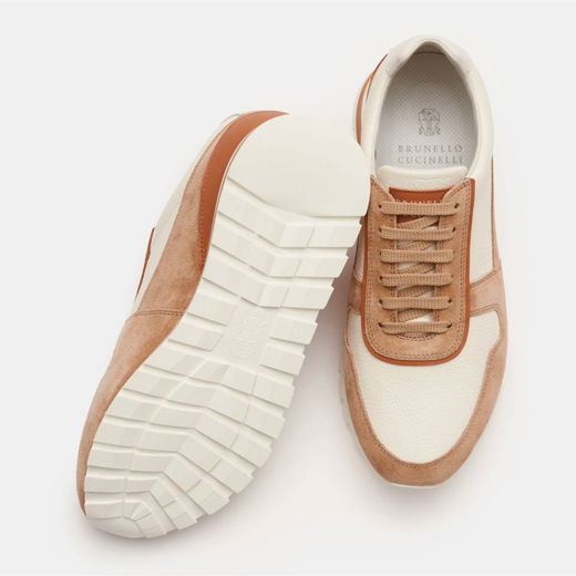 Hellbraune und cremefarbene Herren-Sneaker aus Leder und Wildleder, eine Schuhsohle sichtbar, Vogelperspektive, Marke Brunello Cucinelli.