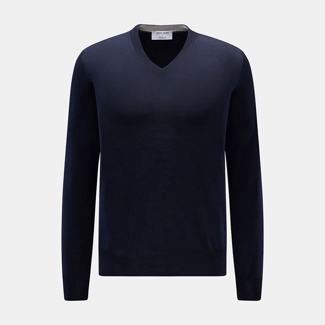 Dunkelblauer Herrenpullover mit V-Ausschnitt, langärmlig, schmal geschnitten, aus feinem Strickmaterial vor hellem Hintergrund.