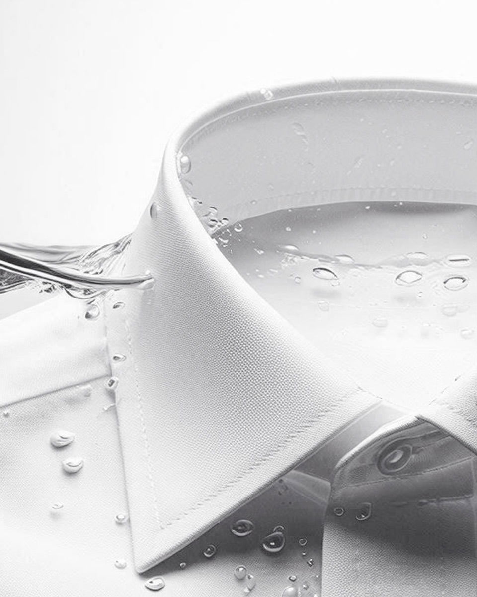 Weißes Hemd mit Kent-Kragen, umspült von spritzendem Wasser, das Frische und Sauberkeit symbolisiert.