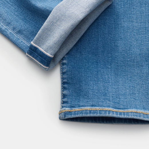 Nahaufnahme eines umgeschlagenen Saums einer blauen Selvedge-Denim-Jeans für Herren mit sichtbarer weiß-roter Kante.