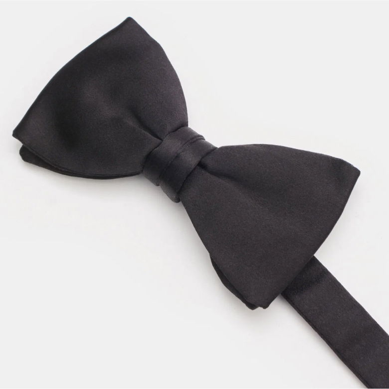 Schwarze, elegant gelegte Smoking-Schleife aus Satin mit breitem Band vor hellem Hintergrund, Nahaufnahme.
