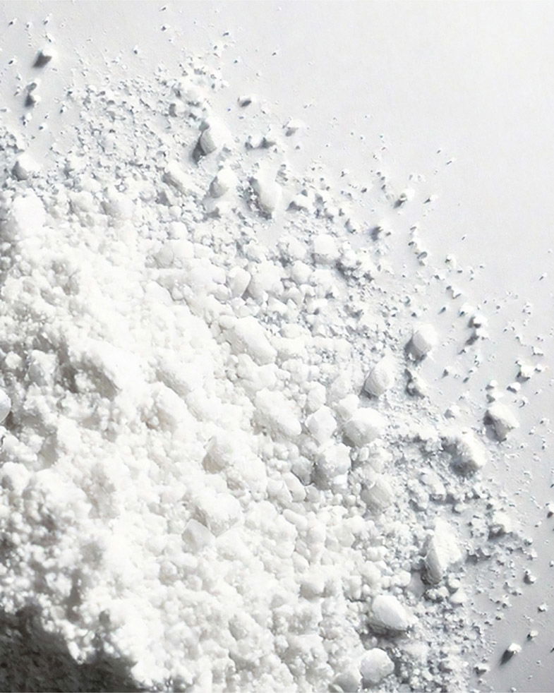 Nahaufnahme von weißem, grobkörnigem Backpulver, das auf einer glatten weißen Oberfläche verstreut liegt.