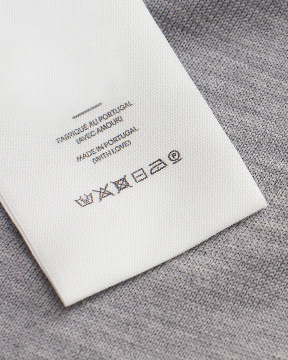 Detailansicht des Pflegeetiketts eines Wollpullovers in hellgrau Detailansicht des Pflegeetiketts eines Wollpullovers in hellgrau