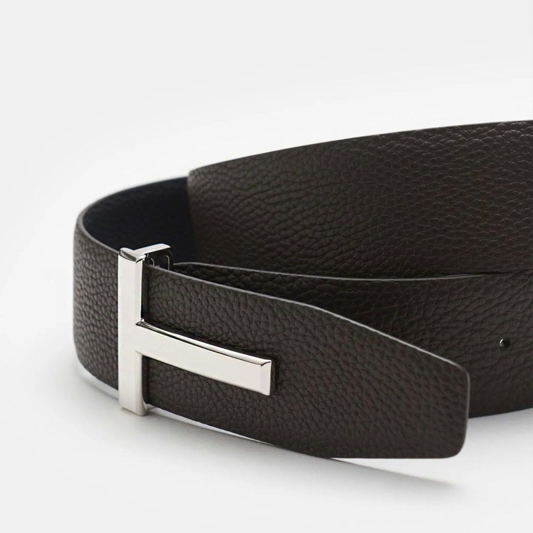 Schwarzer Leder-Gürtel mit feiner Narbenstruktur und silberner Designer-Schließe in geprägter Logoform, liegend. Schwarzer Leder-Gürtel mit feiner Narbenstruktur und silberner Designer-Schließe in geprägter Logoform, liegend.