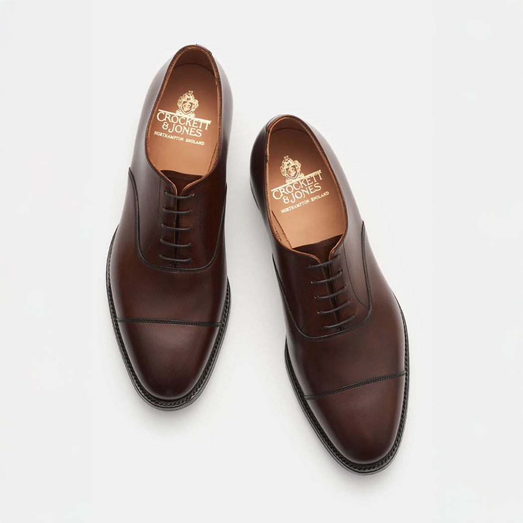 Herren-Schnürschuhe aus dunkelbraunem Leder, von oben fotografiert, mit feiner Naht und Marke Crockett & Jones im Inneren.
