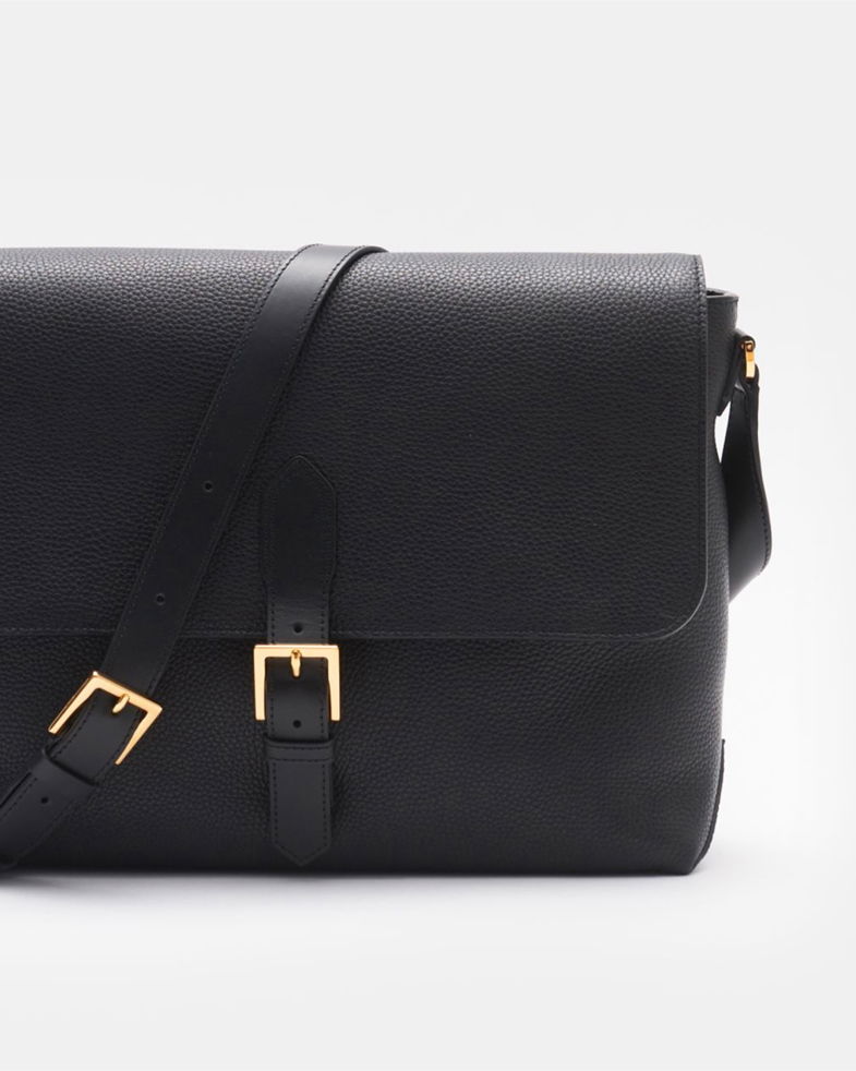 Schwarze Umhängetasche aus genarbtem Leder mit verstellbarem Schultergurt und goldfarbenen Schnallen, Vorderansicht. Schwarze Umhängetasche aus genarbtem Leder mit verstellbarem Schultergurt und goldfarbenen Schnallen, Vorderansicht.