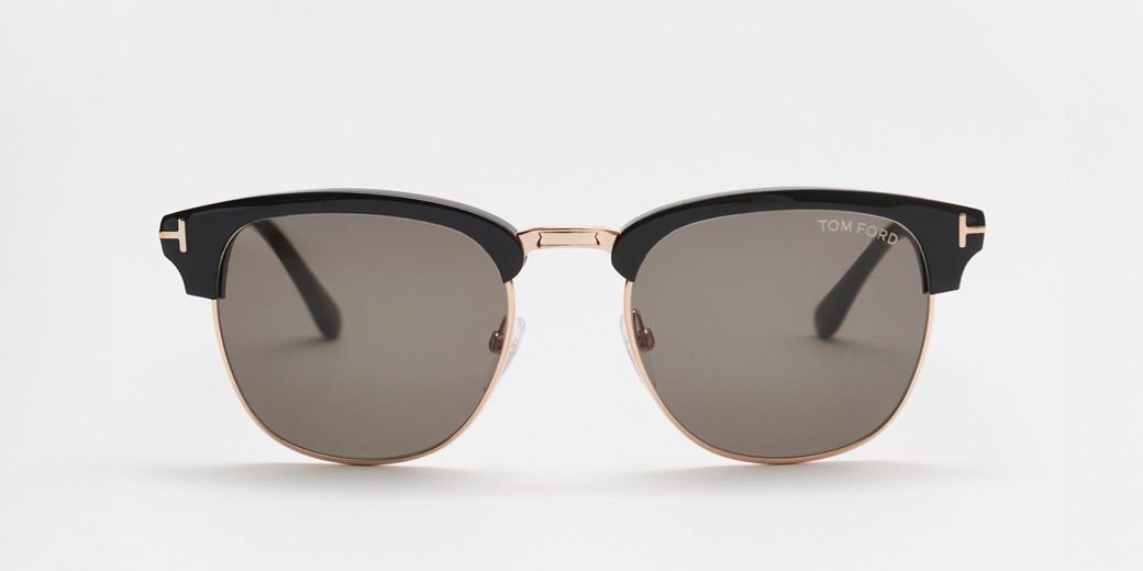 Herrensonnenbrille mit schwarzem Rahmen, goldfarbenem Rand und braunen Gläsern, frontal auf weißem Hintergrund.