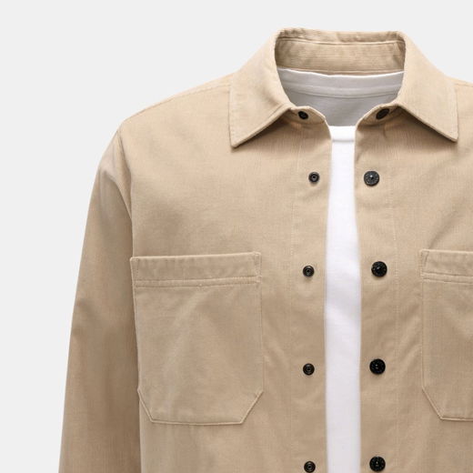 Beige Overshirt mit Knopfleiste und zwei Brusttaschen, getragen über einem weißen T-Shirt, Vorderansicht ohne Person.