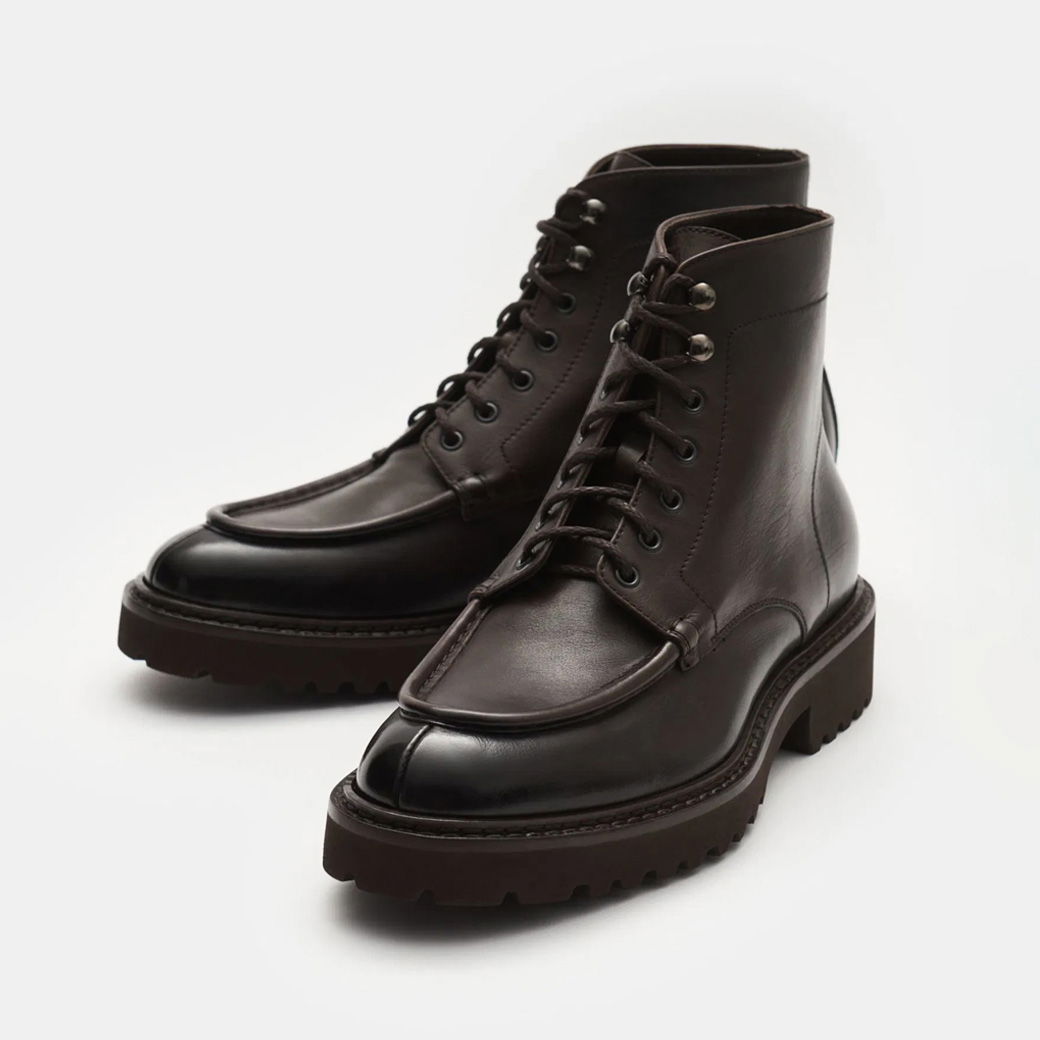 Dunkelbraune Herren-Schnürboots aus Leder mit robuster Profilsohle, Metallösen und markanter Vorderansicht.