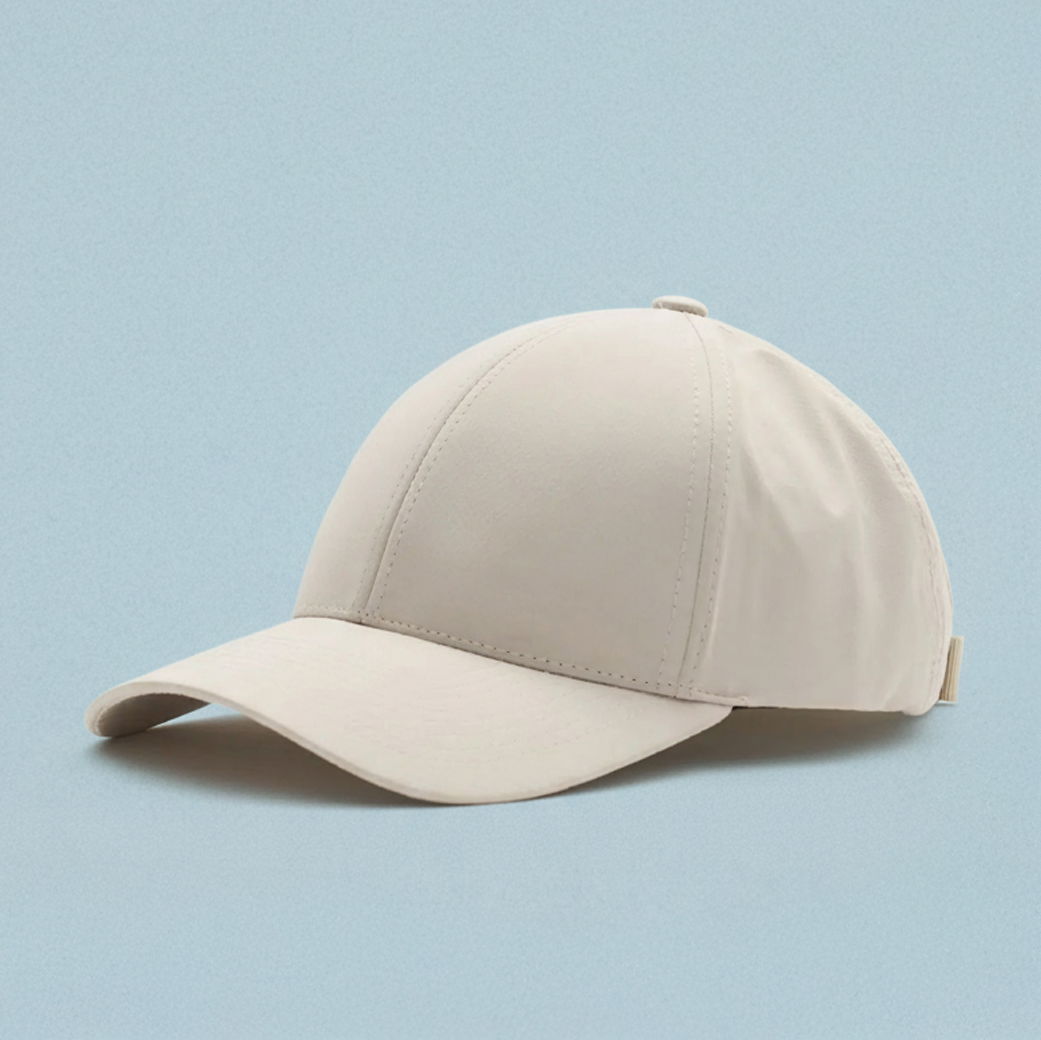 Weiße Baseballcap aus Stoff mit gebogenem Schirm, seitlicher Verstellriemen, vor hellblauem Hintergrund liegend. Weiße Baseballcap aus Stoff mit gebogenem Schirm, seitlicher Verstellriemen, vor hellblauem Hintergrund liegend.