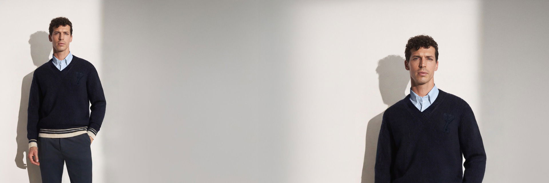 Mann trägt dunkelblauen Pullover mit V-Ausschnitt, hellblaues Hemd, blaue Hose, steht vor heller Wand, Nah- und Fernansicht. Mann trägt dunkelblauen Pullover mit V-Ausschnitt, hellblaues Hemd, blaue Hose, steht vor heller Wand, Nah- und Fernansicht.