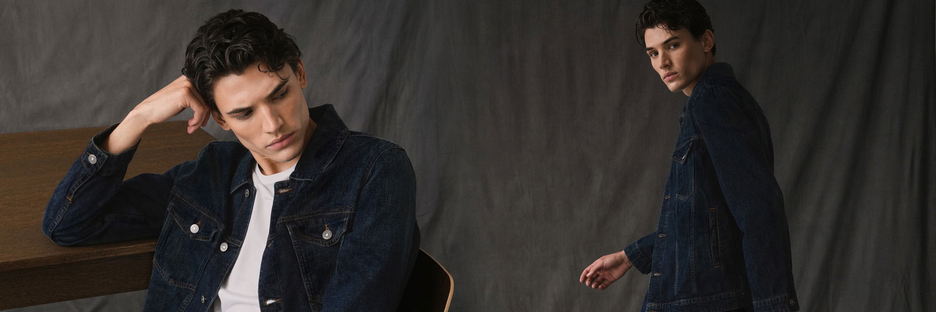 Zwei Ansichten eines jungen Mannes in blauer Jeansjacke, sitzend und stehend vor grauem Hintergrund. Zwei Ansichten eines jungen Mannes in blauer Jeansjacke, sitzend und stehend vor grauem Hintergrund.