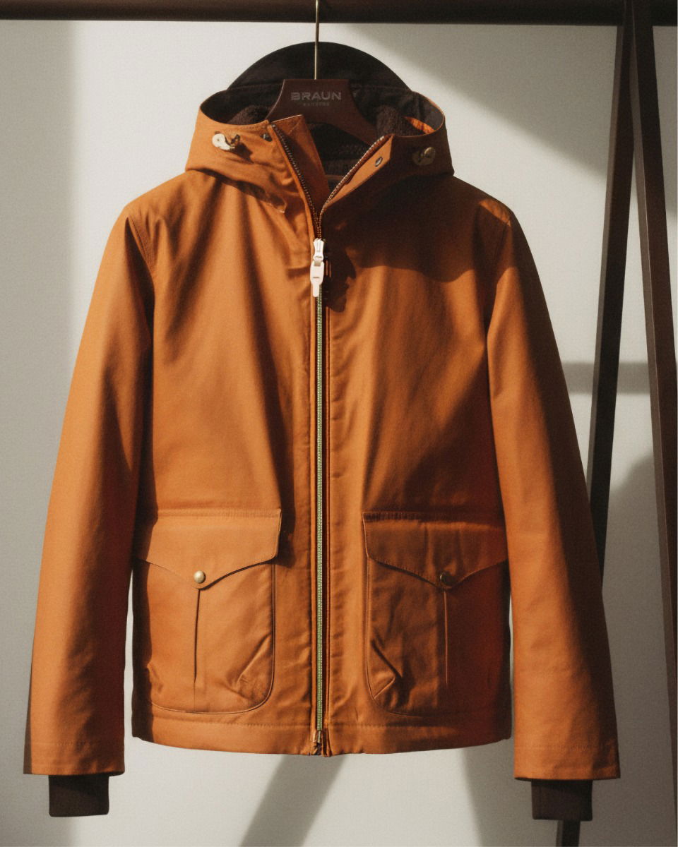 Braune Jacke mit Kapuze, zwei großen Taschen und Reißverschluss, aufgehängt an einem Holzkleiderbügel vor hellem Hintergrund. Braune Jacke mit Kapuze, zwei großen Taschen und Reißverschluss, aufgehängt an einem Holzkleiderbügel vor hellem Hintergrund.