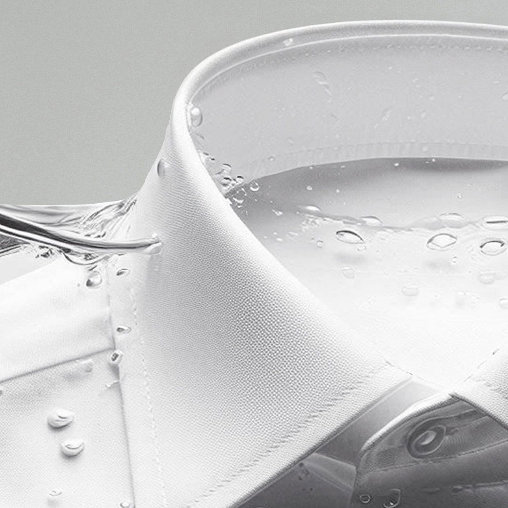 Detailaufnahme eines weißen Herrenhemd-Kragens, umgeben von klaren Wasserblasen und Wassertropfen.