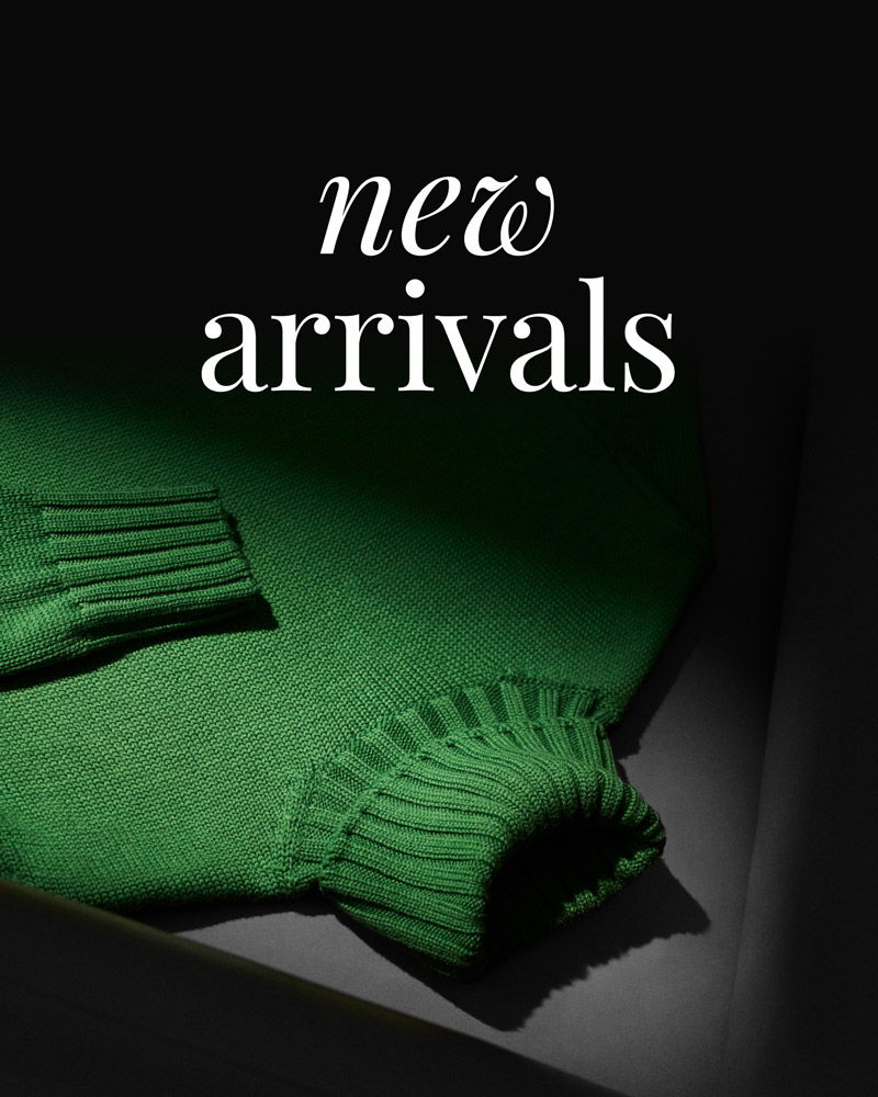 Green knitted sweater displayed in a dark setting with the text 'new arrivals' above it in white elegant font.