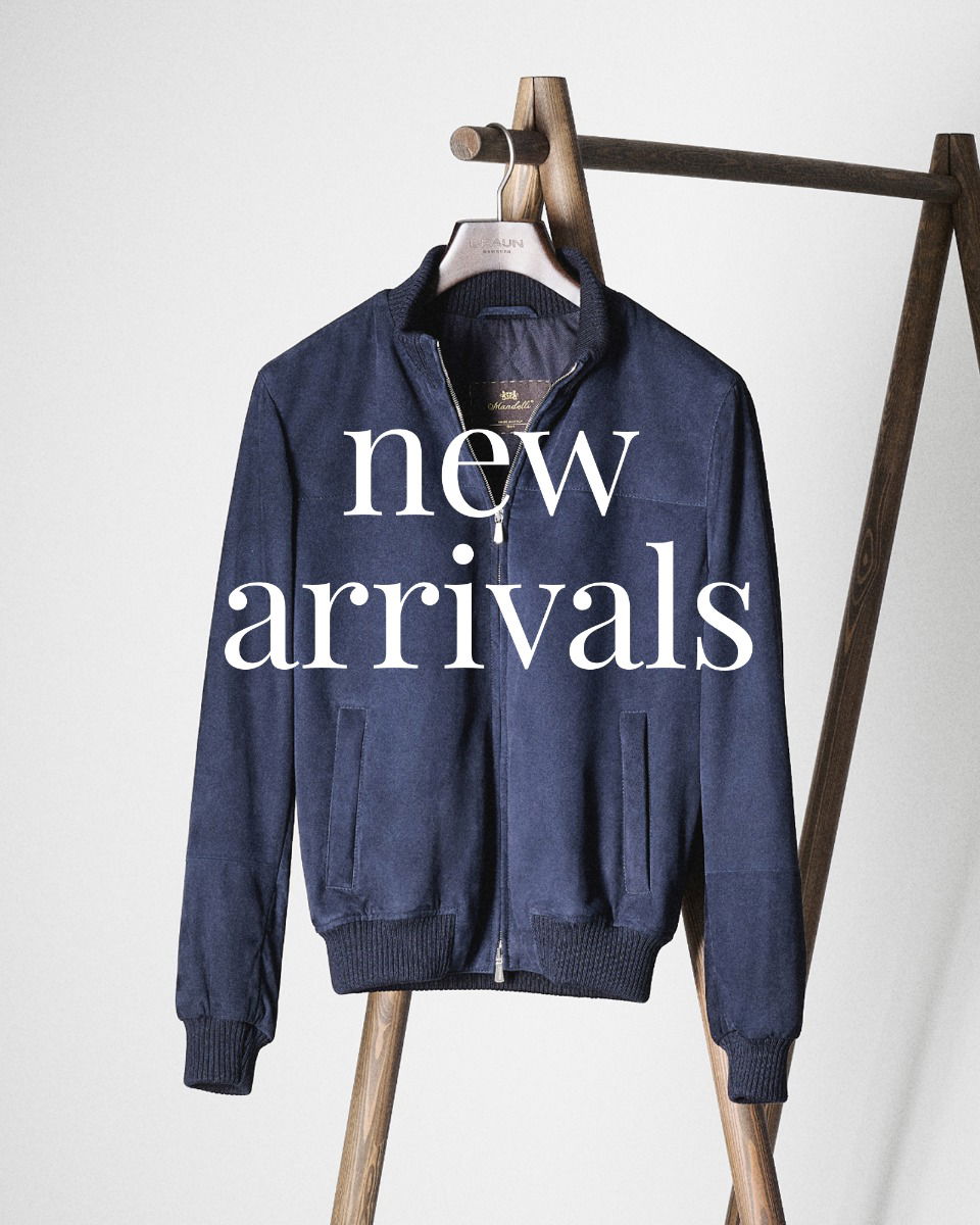 Navy blue zip-up bomber jacket hanging on a wooden clothing rack with 'new arrivals' text overlay.