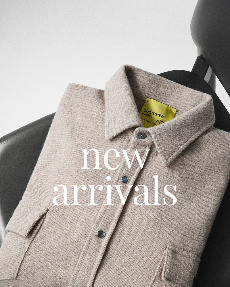 Beige gefaltetes Hemd mit Knöpfen und Taschen liegt auf einem schwarzen Stuhl, Text 'new arrivals' darüber.