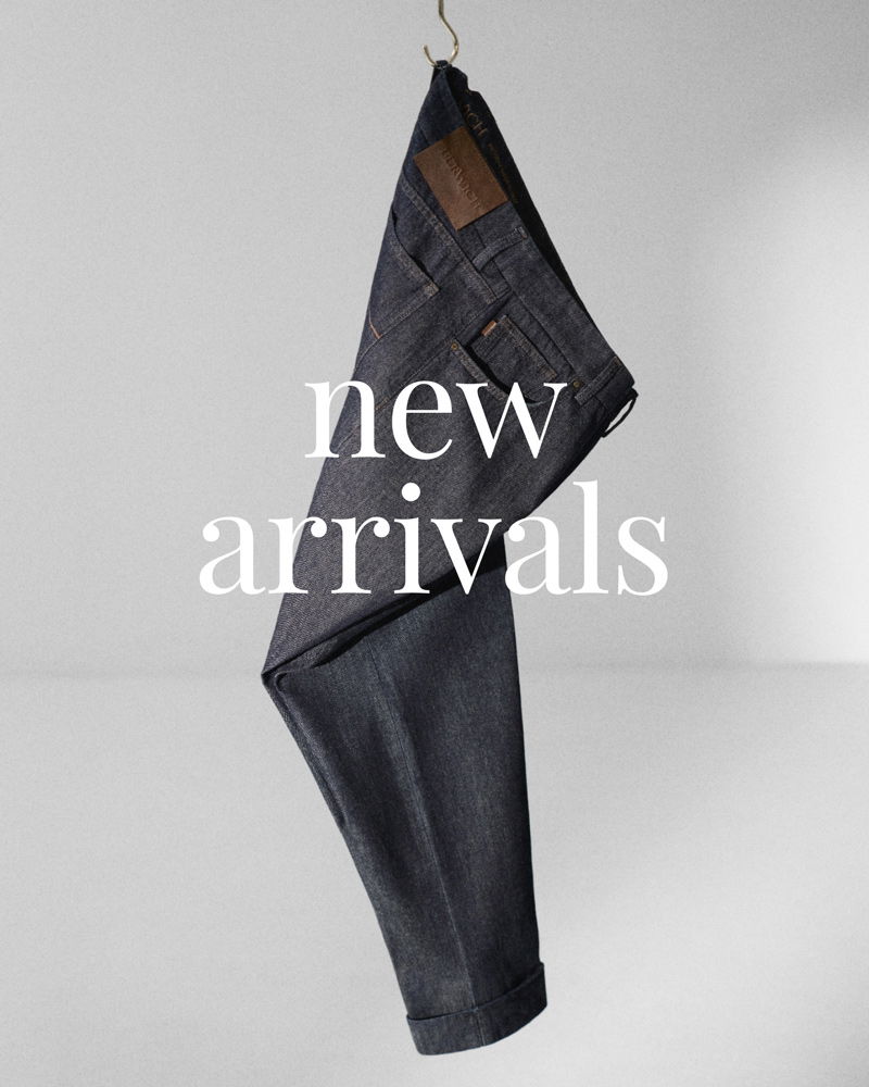 Jeanshose aus dunkelblauem Denim, an einem Kleiderbügel hängend, mit Text 'new arrivals' vor hellem Hintergrund.