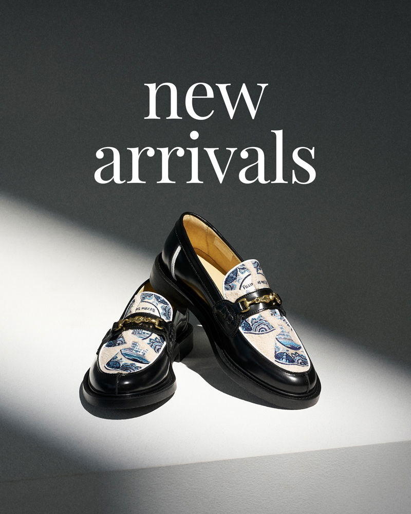 Schwarze Loafer mit blau-weiß gemustertem Stoffeinsatz und goldfarbenem Detail, auf hell-dunklem Hintergrund vor Text 'new arrivals'.