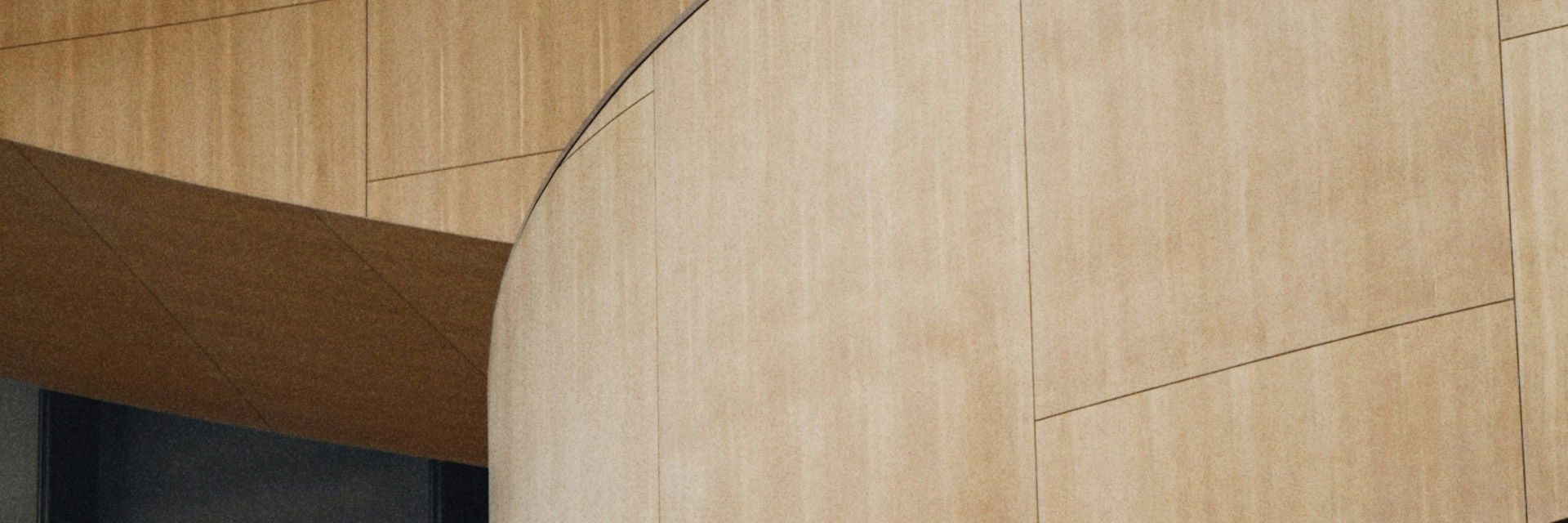 Curved beige wooden wall panels with rectangular patterns and a dark recess on the left side. Curved beige wooden wall panels with rectangular patterns and a dark recess on the left side.