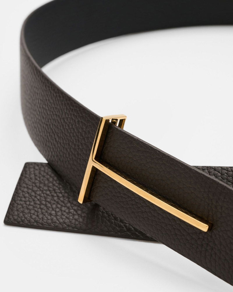 Dunkelbrauner Ledergürtel mit strukturierter Oberfläche und goldfarbener, rechteckiger Schnalle auf weißem Hintergrund.