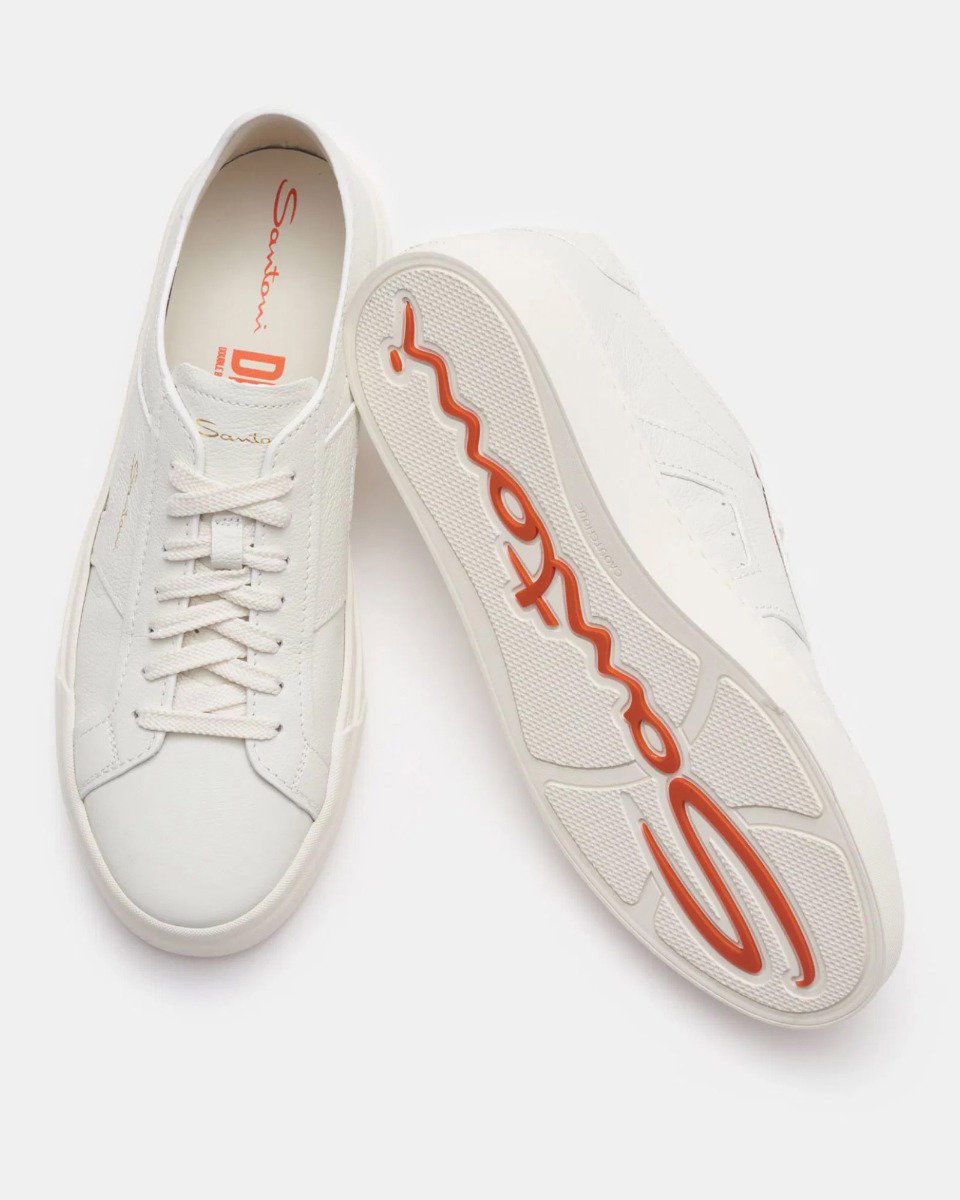 Pair of white Santoni leather sneakers, one showing top with laces, the other showing sole with orange Santoni logo.