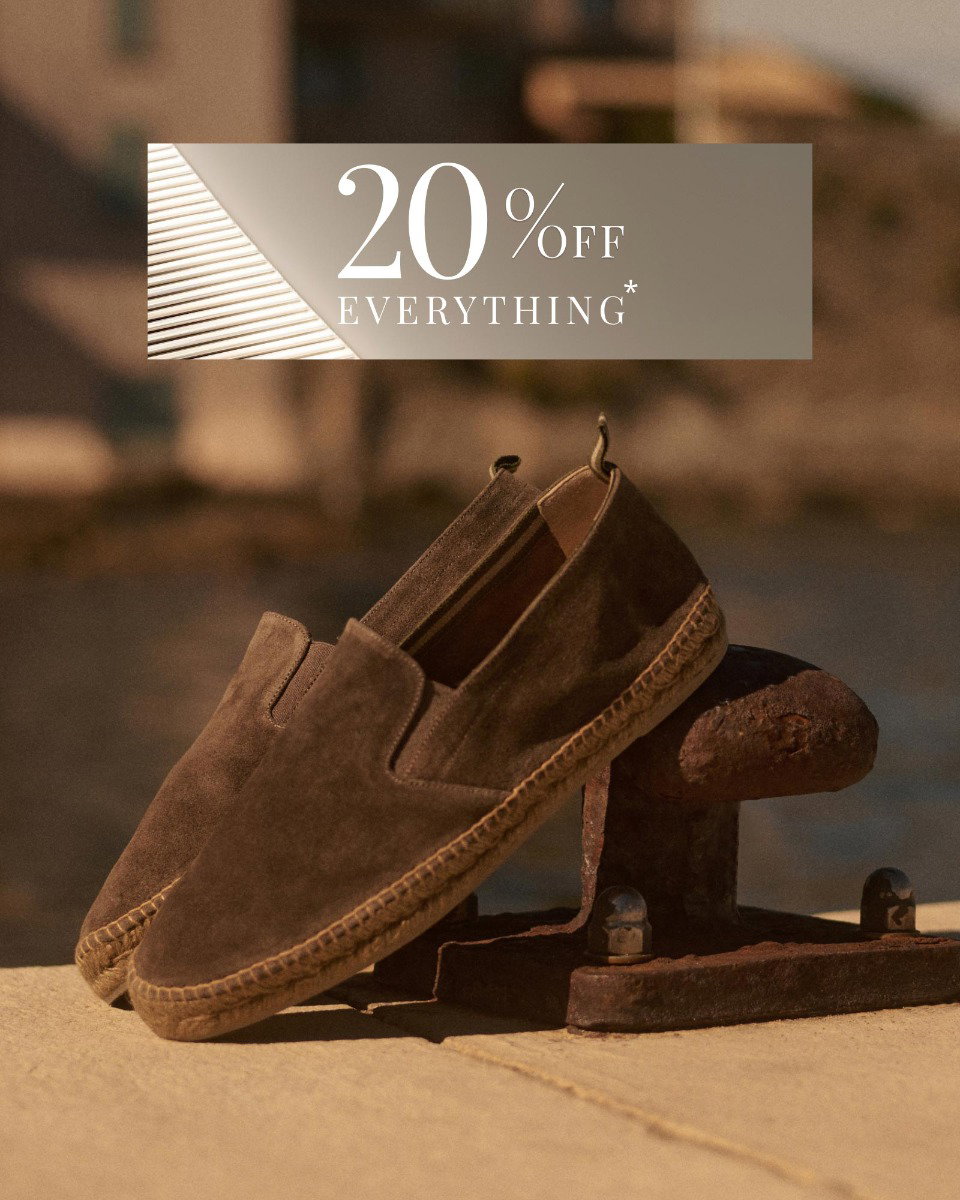 Braune Wildleder-Espadrilles mit geflochtener Sohle, auf rostigem Hafenpoller stehend bei Sonnenlicht.