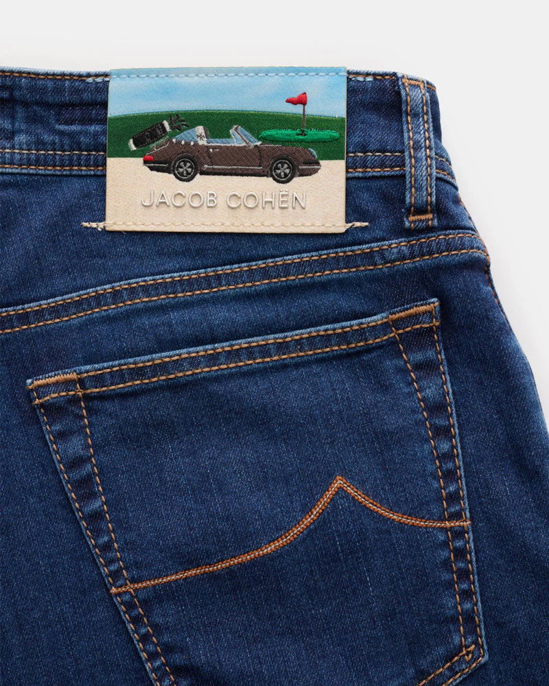 Jeansrückseite mit braunem Cabrio und Golfplatz-Stickerei sowie dem Schriftzug 'JACOB COHËN' auf dem Lederetikett.
