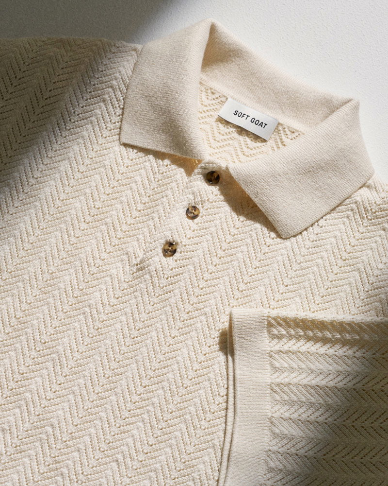 Beige Strick-Poloshirt mit Zickzackmuster, drei braune Knöpfe und Soft Goat Markenlabel am Kragen.