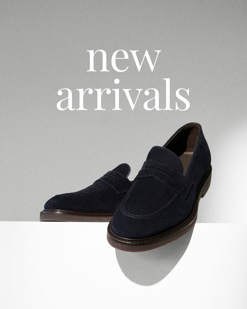 Dunkelblaue Wildleder-Herrenschuhe auf hellgrauem Hintergrund mit dem weißen Schriftzug „new arrivals“.