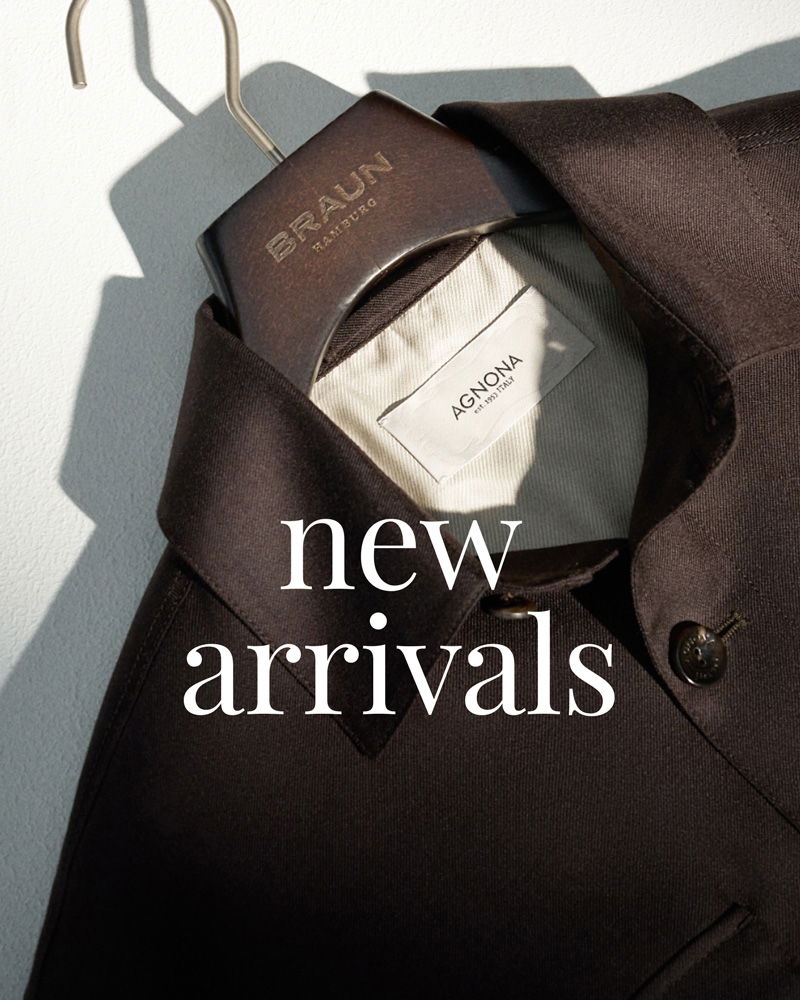 Dunkelbrauner Mantel mit sichtbarem AGNONA Etikett, auf Holzbügel mit Aufschrift BRAUN HAMBURG, Text 'new arrivals'.