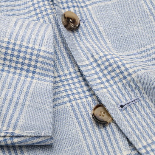 Leichtes blau-weiß kariertes Sakko mit braunen Knöpfen und sichtbarem Ärmel im Detail.