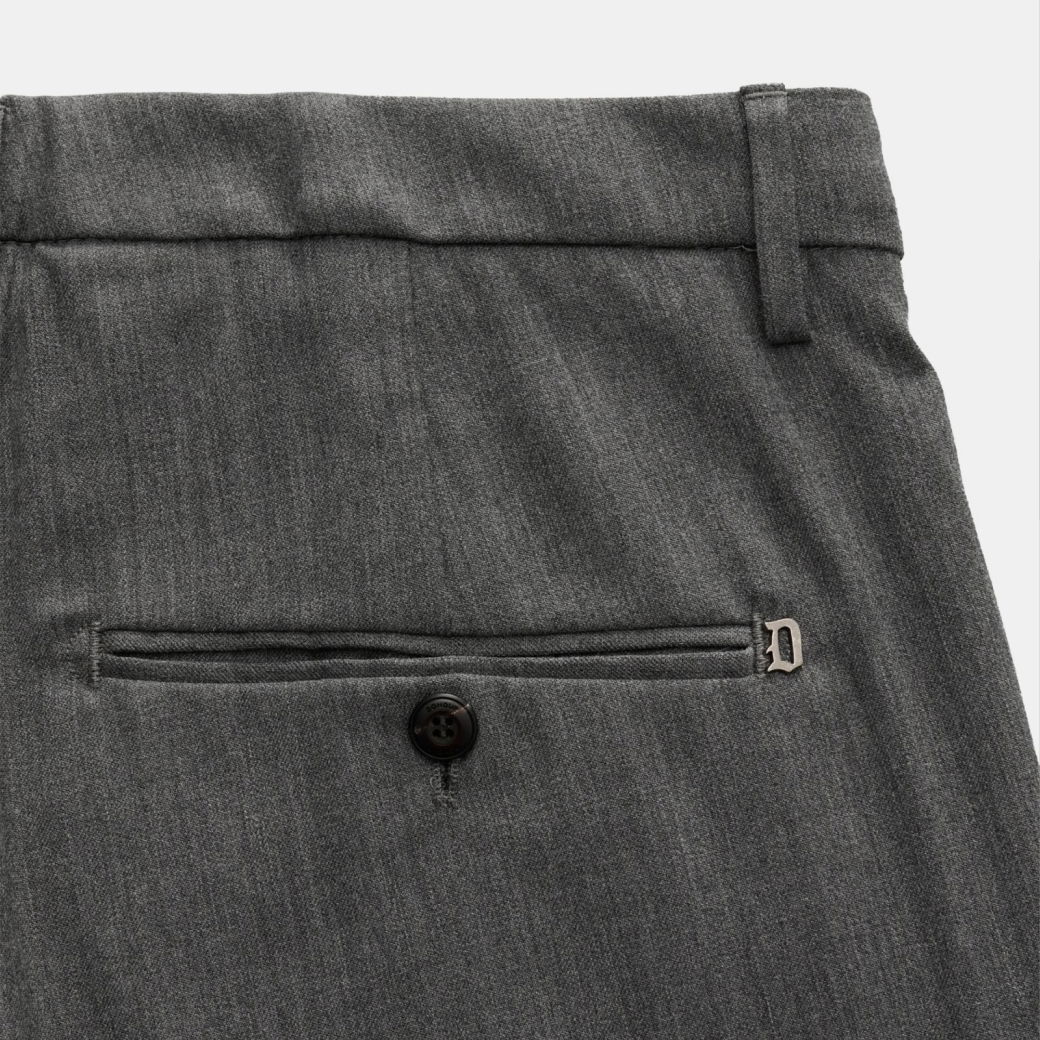 Graue Wollhose mit Gürtelschlaufen, einer geknöpften Gesäßtasche und einem kleinen silbernen Metall-Logo am Bund. Graue Wollhose mit Gürtelschlaufen, einer geknöpften Gesäßtasche und einem kleinen silbernen Metall-Logo am Bund.