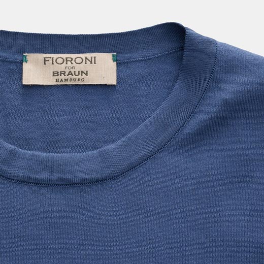 Blaues T-Shirt mit Rundhalsausschnitt und einem weißen Stoffetikett mit der Aufschrift 'Fioroni for Braun Hamburg' am Kragen.