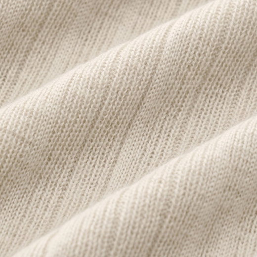 Beige gestrickter Stoff mit feiner, gleichmäßiger Struktur und diagonalen Falten, Nahaufnahme der Textur.