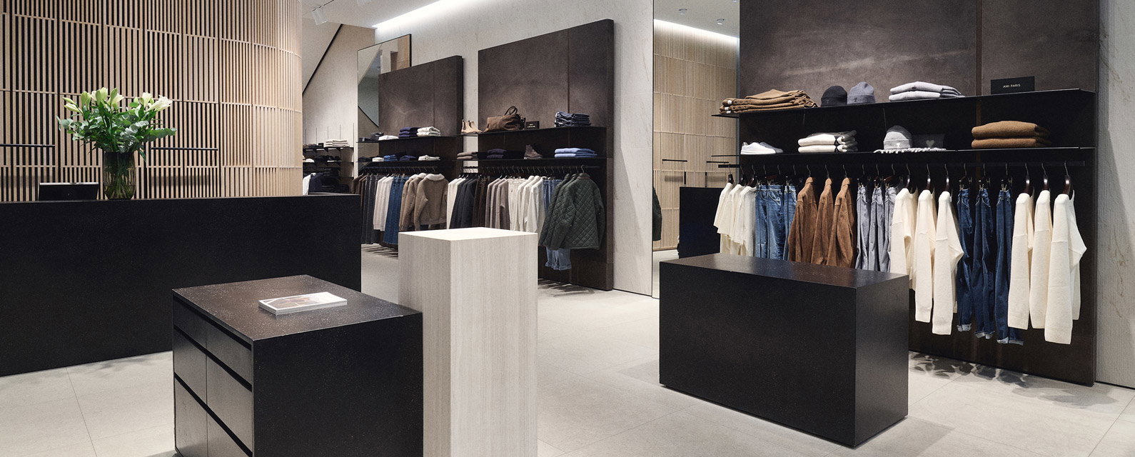 Moderner, minimalistisch eingerichteter Mode-Store mit schwarzen Möbeln, Spiegeln und Kleidung an Kleiderstangen. Moderner, minimalistisch eingerichteter Mode-Store mit schwarzen Möbeln, Spiegeln und Kleidung an Kleiderstangen.