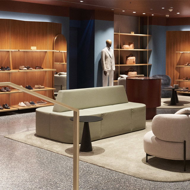 Moderne Herrenausstattung mit grauem Anzug auf Schaufensterpuppe, Lederschuhe, Taschen, Sofa und Sessel in elegantem Geschäft. Moderne Herrenausstattung mit grauem Anzug auf Schaufensterpuppe, Lederschuhe, Taschen, Sofa und Sessel in elegantem Geschäft.