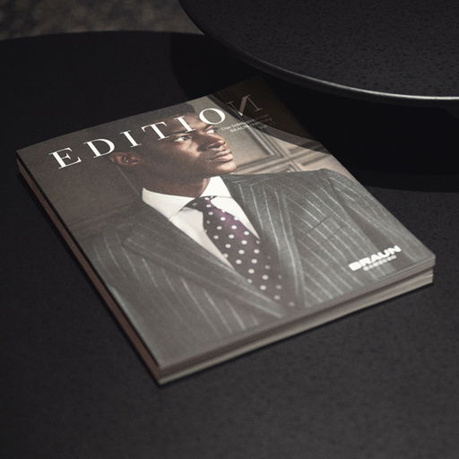 Magazin 'EDITION' mit einem Mann im grauen Nadelstreifenanzug und gepunkteter Krawatte auf dem Cover, liegt auf dunklem Tisch. Magazin 'EDITION' mit einem Mann im grauen Nadelstreifenanzug und gepunkteter Krawatte auf dem Cover, liegt auf dunklem Tisch.