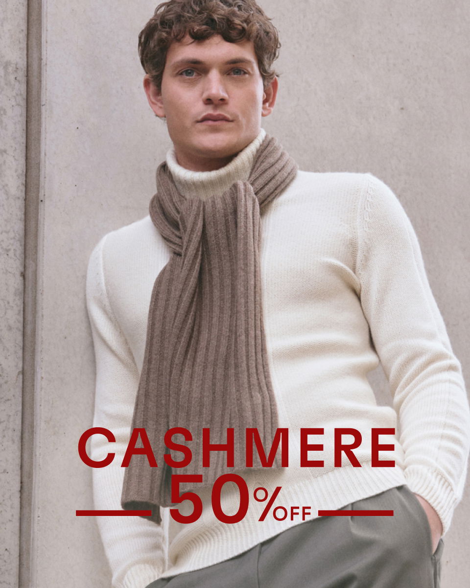 Mann trägt cremefarbenen Rollkragenpullover und braunen, gerippten Kaschmirschal, Text 'Cashmere 50% off' in Rot.