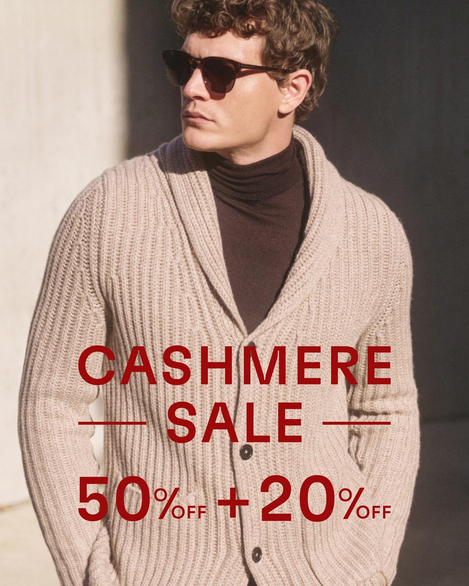 Man wearing dark sunglasses, a brown turtleneck, and a beige chunky knit cashmere cardigan, with sale text overlay.