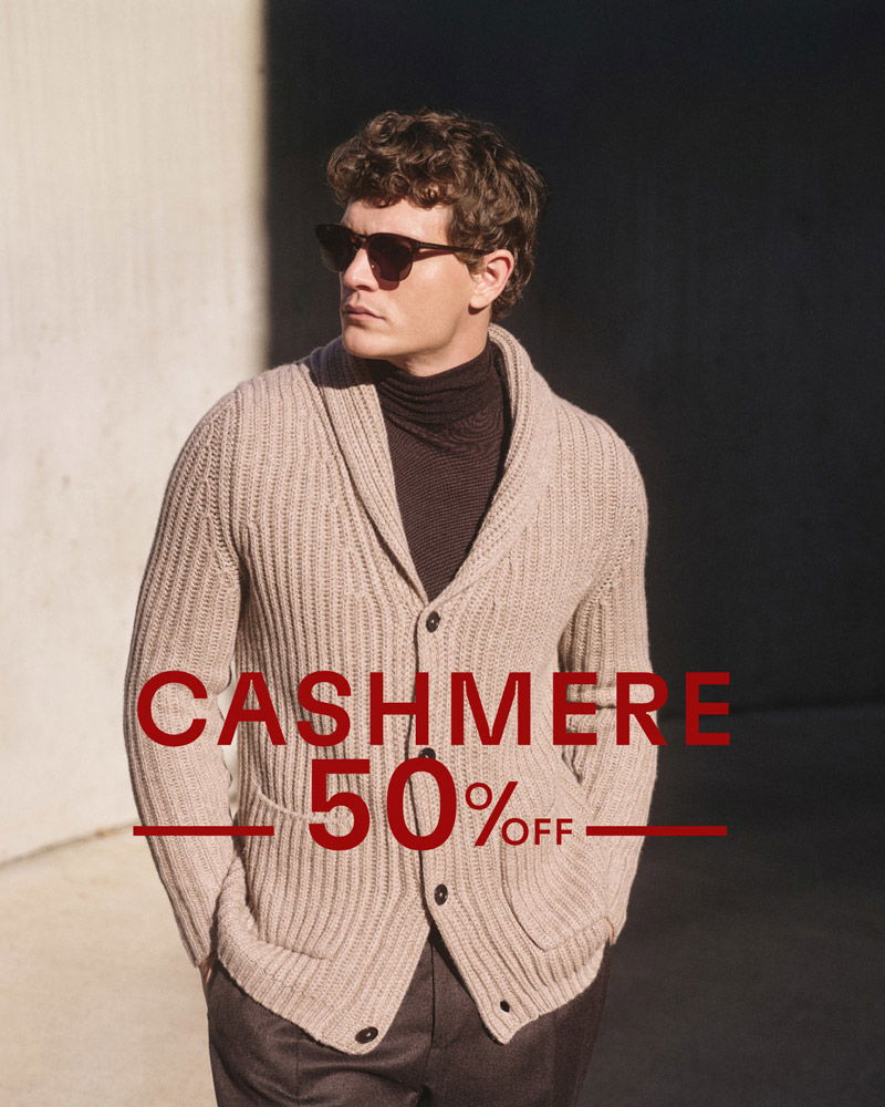 Mann mit brauner Sonnenbrille trägt hellbeige grob gestrickte Cashmere-Strickjacke und dunklen Rollkragenpullover, Sale 50% Rabatt.